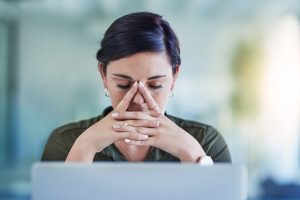 a woman looking at her laptop deep in thought
